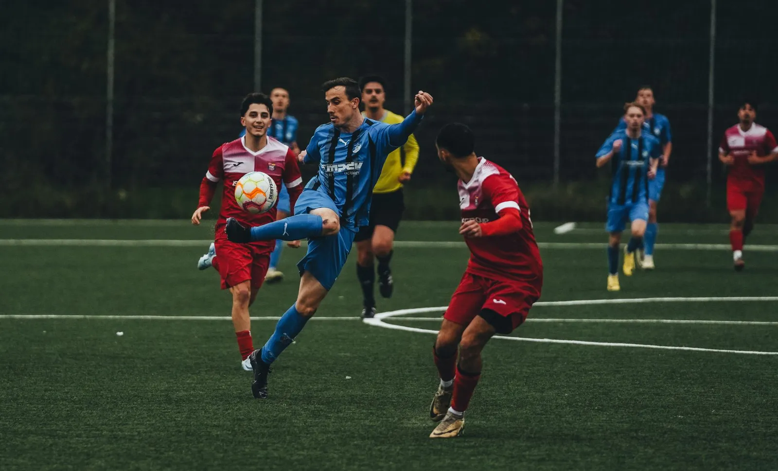 잔디 위에서 동료에게 패스를 연결한 뒤 손을 들어 신호하는 축구 선수의 모습