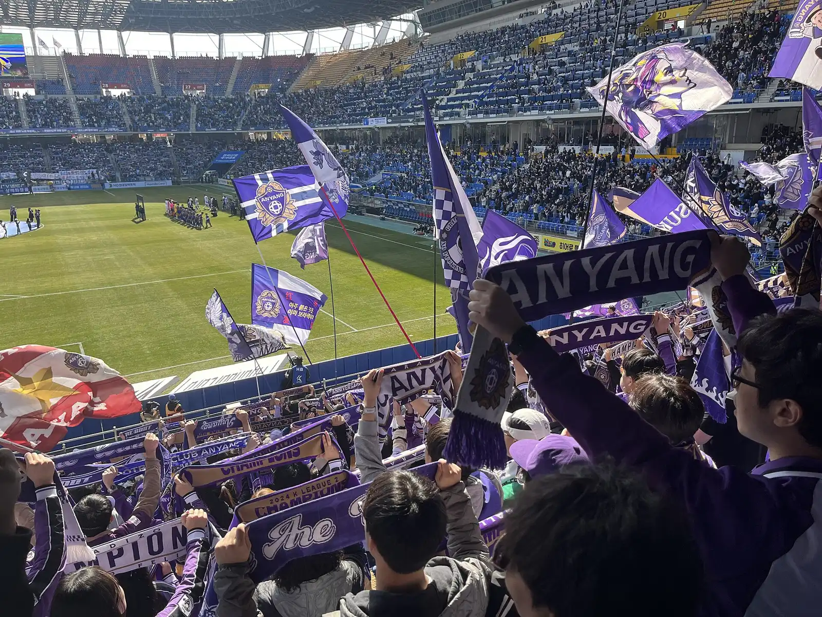 경기장 관중석을 가득 메운 응원 물결과 그 앞에서 서로 하이파이브를 나누는 축구 선수들