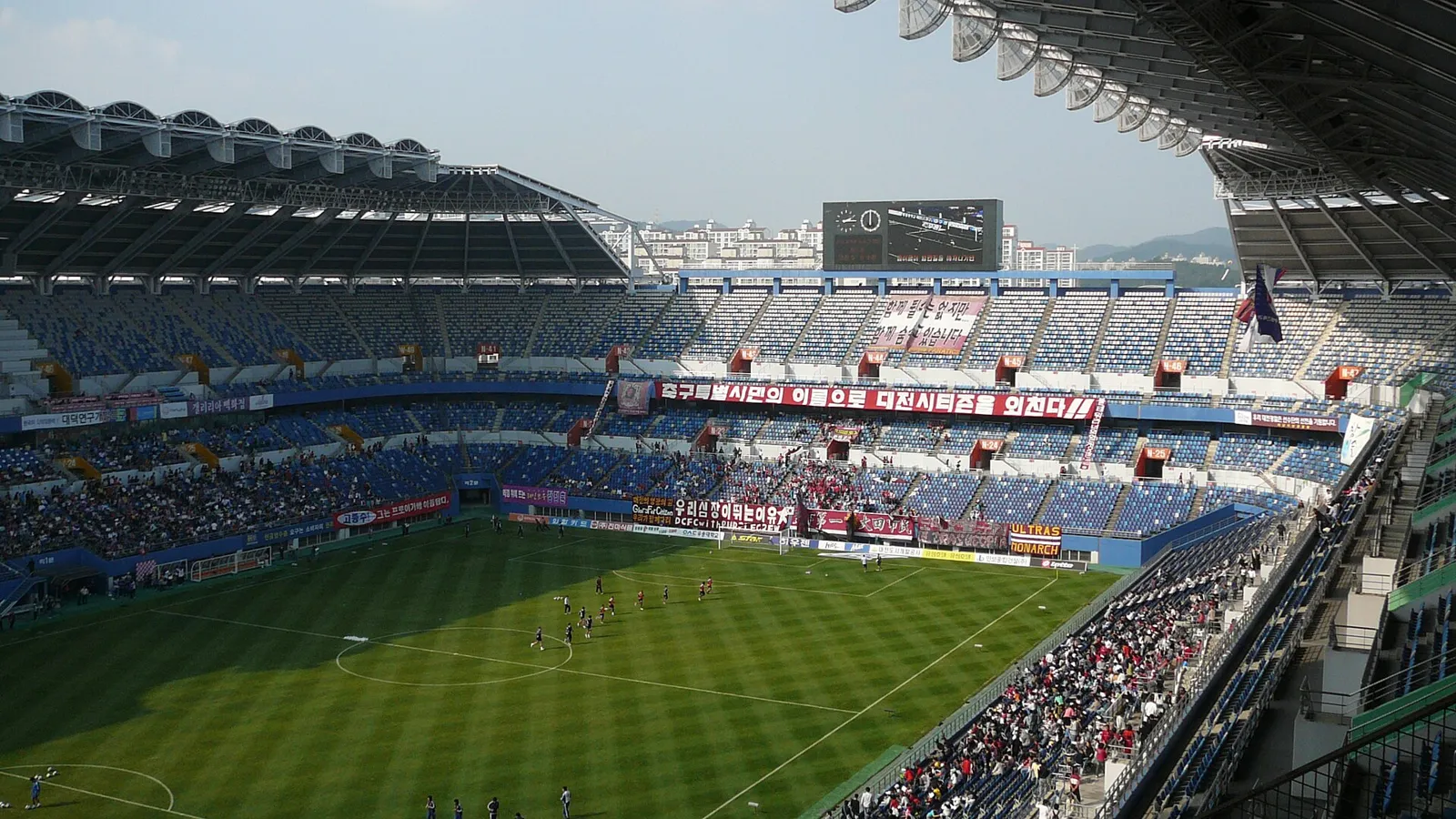 텅 빈 축구장 골대 뒤로 붉은 관중석이 펼쳐진 저녁 무렵의 스타디움 전경